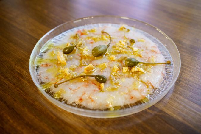 Prawn carpaccio garnished with capers and nut