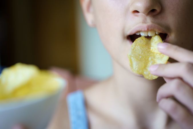 Unrecognizable young girl eating crispy potato chip