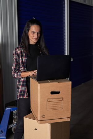 Positive woman browsing laptop near self storage
