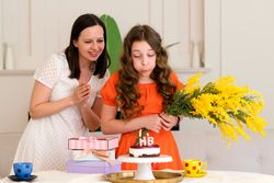 Girl in orange dress blowing out candles on birthday cake