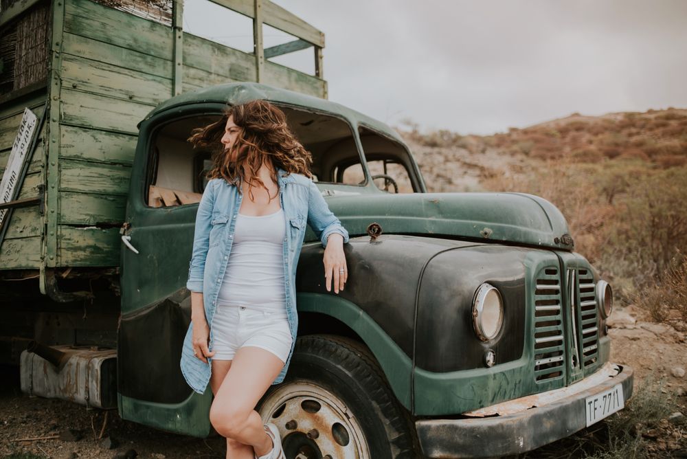 Relaxed female leaning on old truck