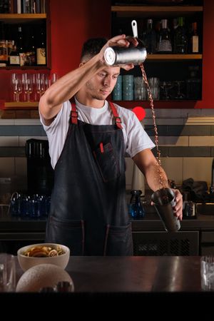 Man pouring alcohol drink into shaker