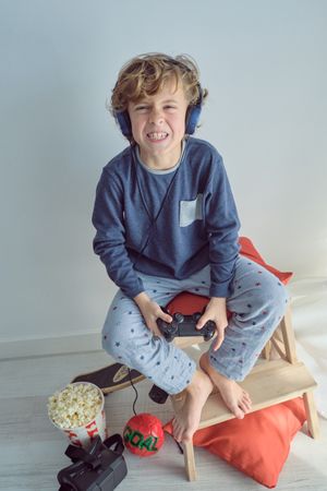 Funny boy in headphones playing game with game pad
