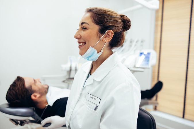 Happy female dentist in dental clinic looking to the side and smiling