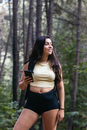 Young woman using her smartphone while hiking in the forest