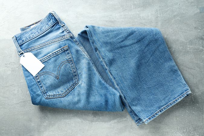 Folded jeans with a tag on a light background