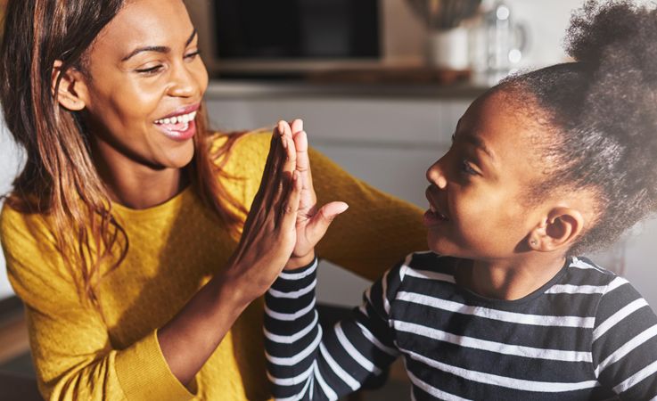 Mother and daughter high five in the kitchen