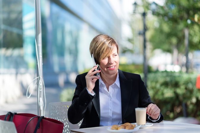 Business woman sitting outside with coffee talking on cell phone