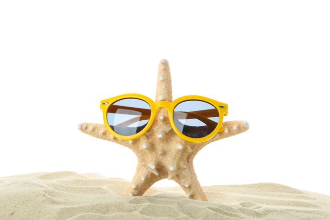 Starfish with sunglasses on clear sea sand isolated on studio background. Summer vacation