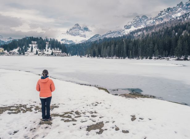 Unrecognizable person standing in snow surrounded by forest and mountains
