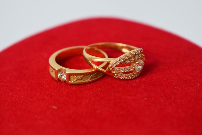 Two diamond gold wedding rings on red material with copy space
