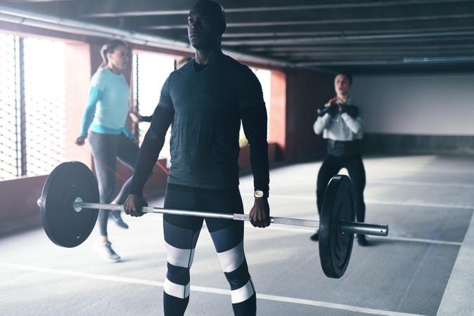 Man doing deadlifts with heavy barbell with other people working out in the background