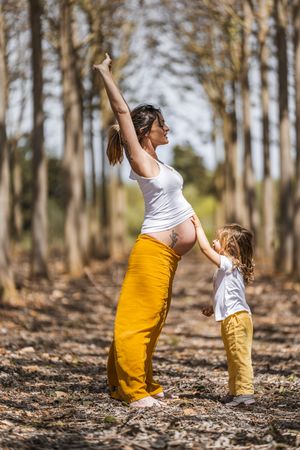 Pregnant mother and little daughter having fun in park