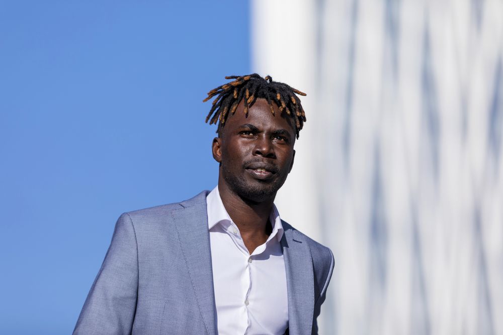 Black man wearing elegant clothes walking in the street while looking in the distance on sunny day