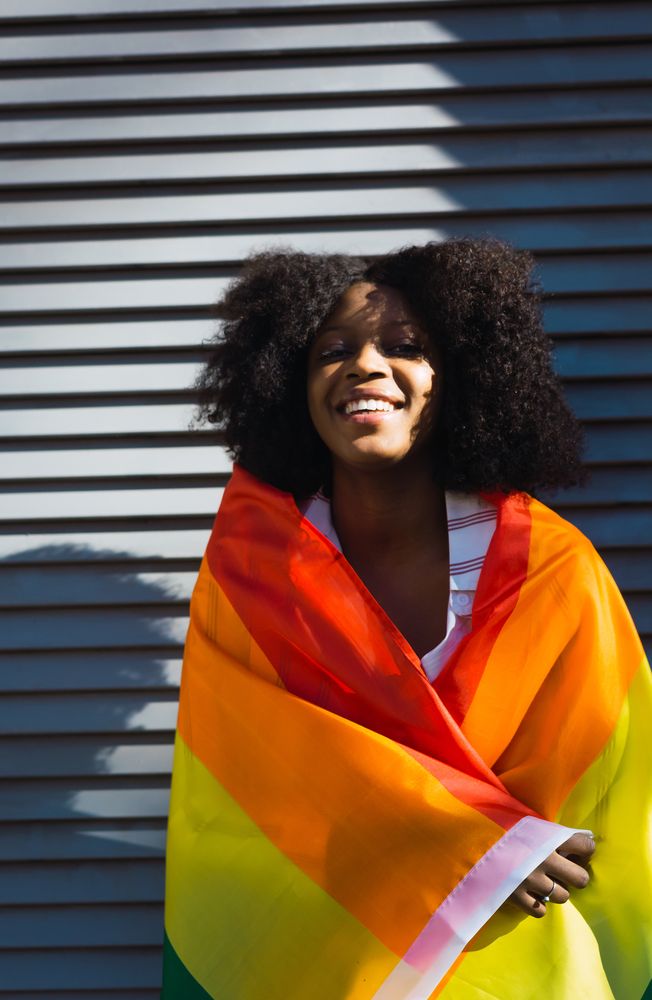 Black woman posing happily with the LGBT flag