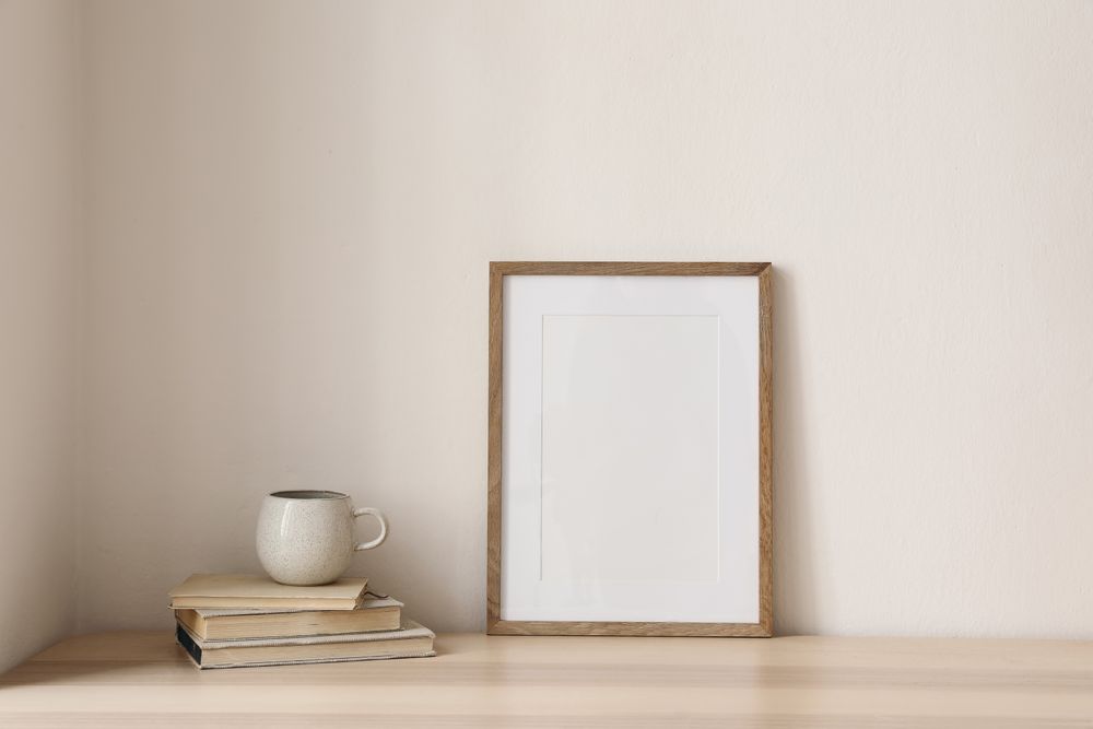 Coffee atop pile of books with blank frame