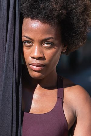 Fit Black woman with hammock for yoga in city