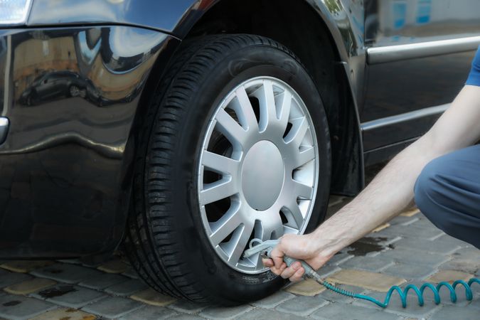 Man pumps up tires. Car inspection. Maintenance