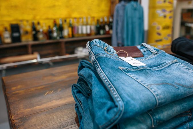 Blue jeans pants stacks over counter on vintage clothes shop with left copy space