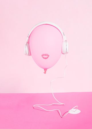 Pink balloon with lips wearing headphones plugged into pink desk