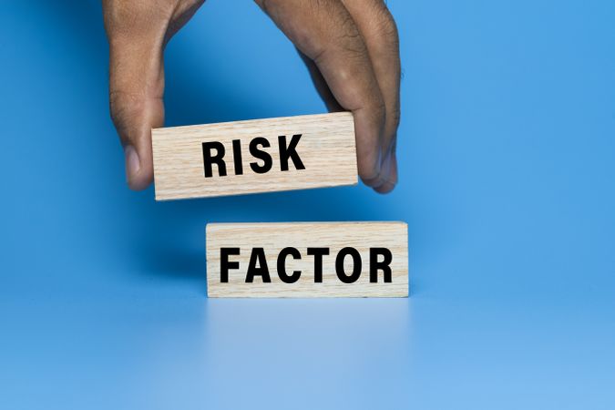 male hand put wooden blocks with risk factor words symbol concept isolated on blue background