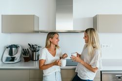 Women with coffee chatting in kitchen