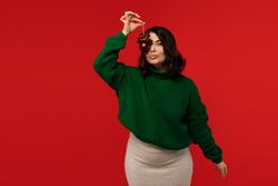 Woman holding red Christmas bauble near her face.