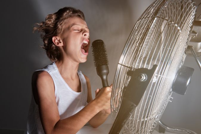 Boy singing into comb in front of working fan