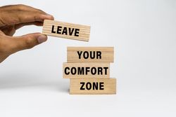 male hand put leave your comfort zone words on wooden blocks isolated on plain background