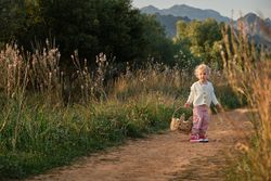 Funny little girl with basket standing on rural road