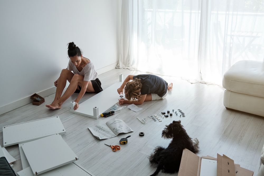 Mother and son assembling table in room with dog