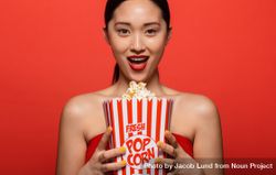Excited woman holding popcorn bucket bYwLY5