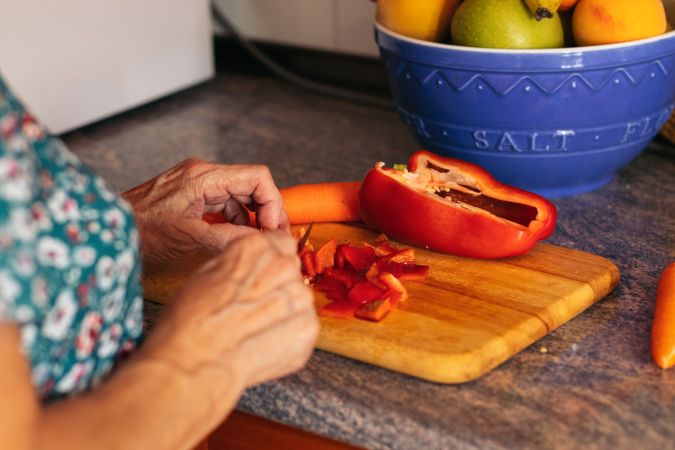 Mature woman cooking with peppers in the kitchen at home