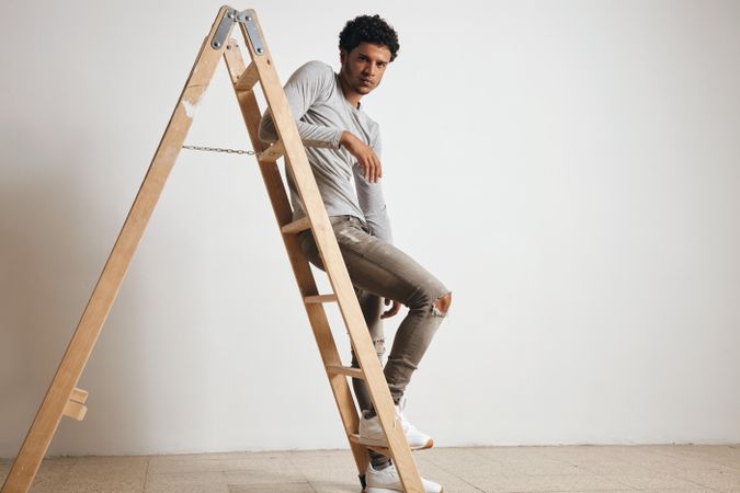 Serious man perched on ladder