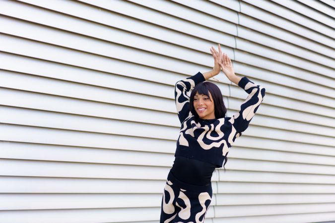 Happy dancer raising hands posing on the street