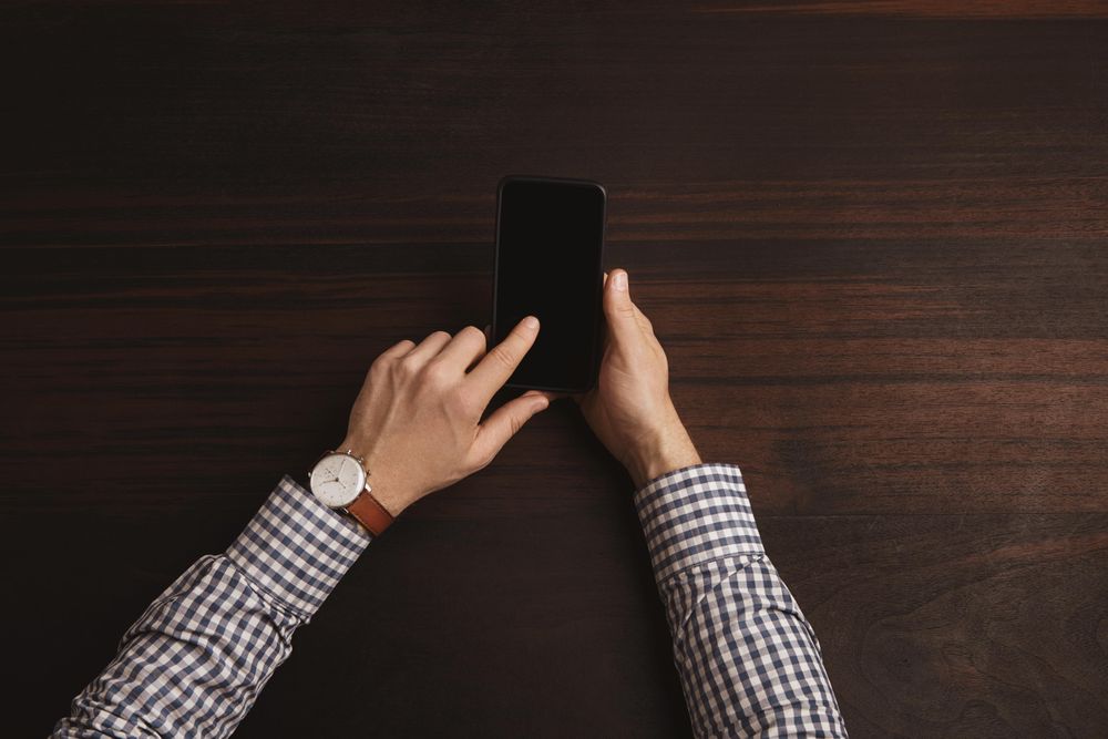 Arms in plaid shirt scrolling on cell phone