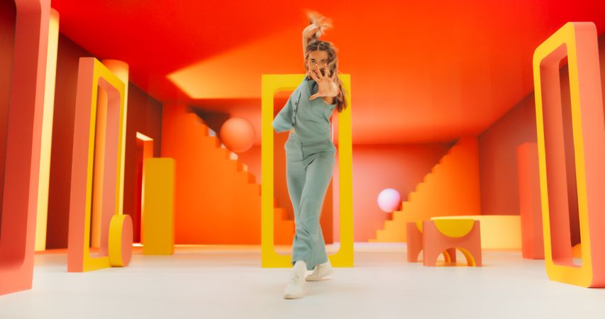 Woman with Bright Makeup Dancing Energetically and Interacting with Colorful Geometric Abstract Environment. Young Female Happily Performing Modern Dance Choreography in a Studio