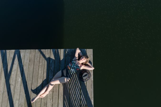 Young female lying down on pier on nature