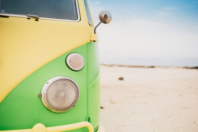 Bright retro minibus with round headlights on beach