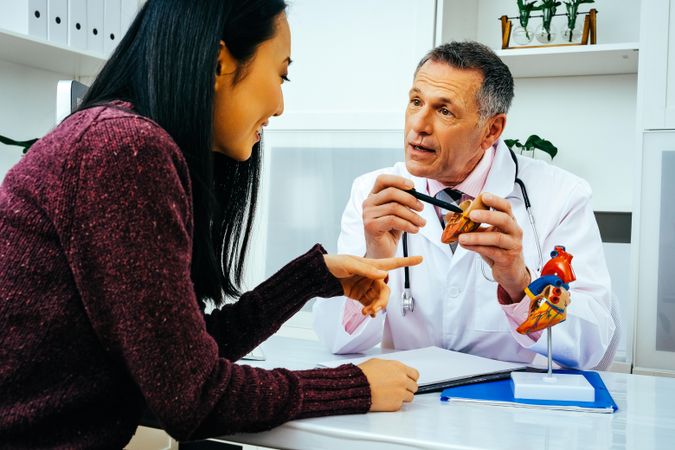 Male doctor with engaged female patient consulting about heart structure