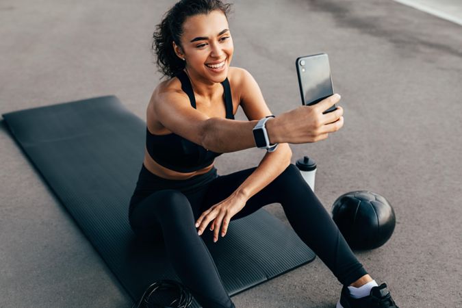 Woman taking a FaceTime call  on exercise mat