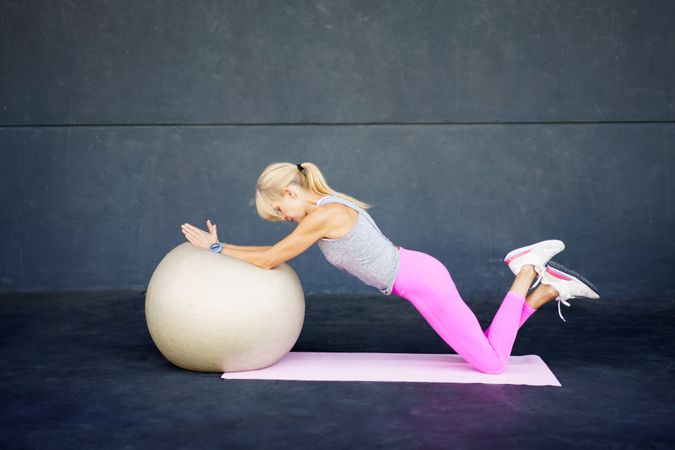 Healthy woman doing mat workout with stability ball