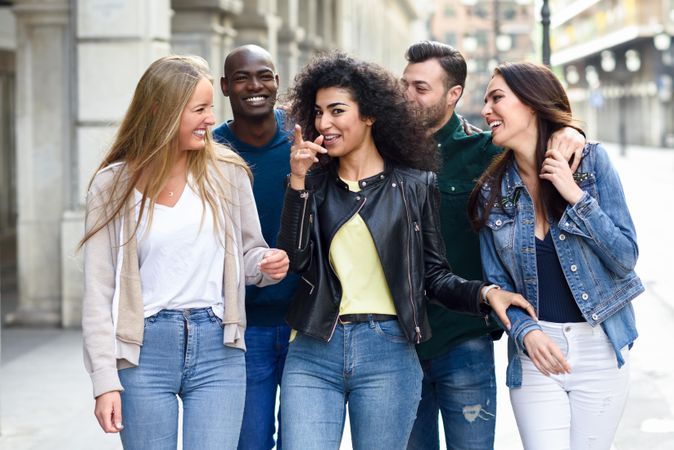 Multi-ethnic friends walking down down city street and smiling together