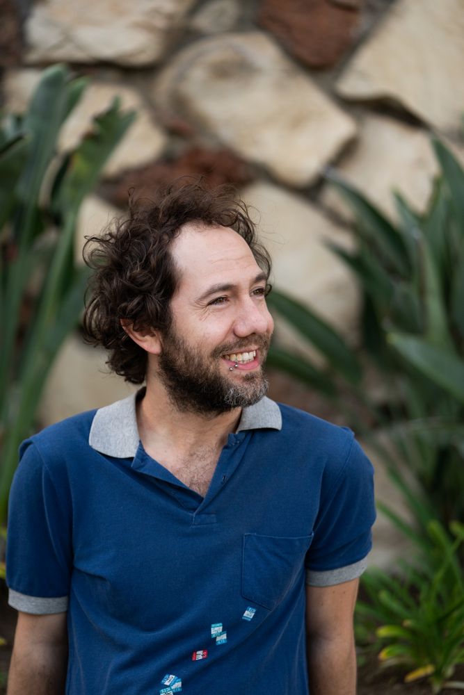 Confident, happy man sitting in front of garden wall smiling and looking away