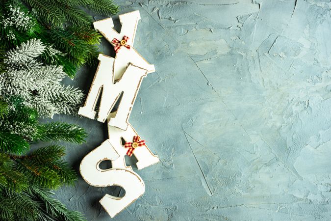 Wintry pine branch with "XMAS" letters on grey background