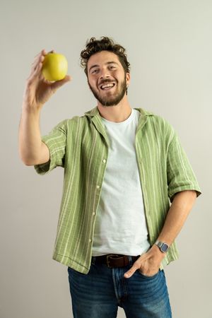 Happy young man holding a fresh apple for a healthy snack.