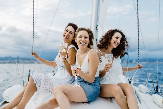 Cheerful friend with wine having fun on yacht