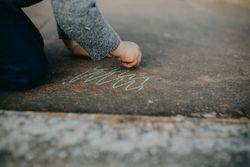 Child drawing squiggles with chalk outside