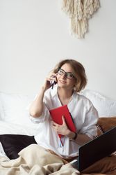 Woman Working From Home In Bed Speaking On Phone