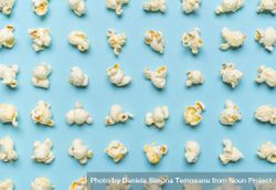 Popcorn flakes aligned on a blue background 5lZWVb